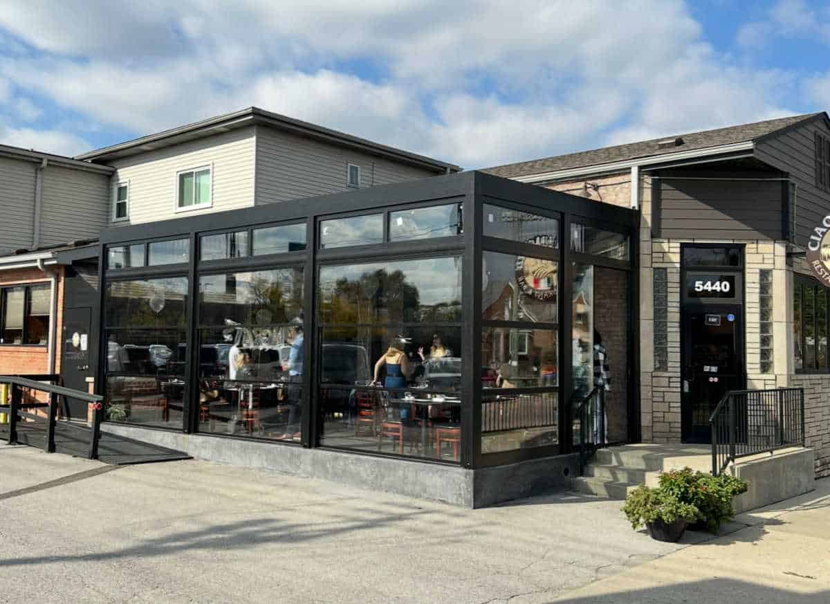 Front exterior of Ciao Ragazzi Restaurant in Chicago, showcasing the modern glass-enclosed patio dining area and main entrance at 5440 address on a sunny day.