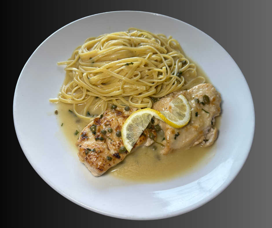 A plate of Chicken Piccata served with linguine, featuring tender chicken breasts in a lemon-butter caper sauce, garnished with fresh lemon slices, on a white plate.